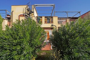 A building with a staircase, a balcony, and a garden area with green plants. - Borgo del Torchio in Manerba del Garda (Manerba del Garda)