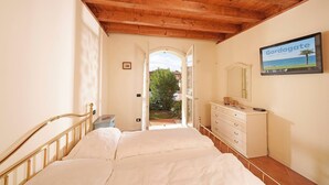A bedroom with a wooden ceiling, a bed, a dresser, and a TV on the wall. - Borgo del Torchio in Manerba del Garda (Manerba del Garda)