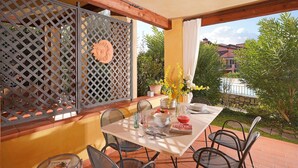 An outdoor patio with a table set for dining, surrounded by chairs, and a decorative fence with a sun motif. - Borgo del Torchio in Manerba del Garda (Manerba del Garda)
