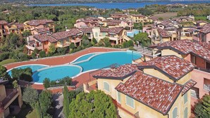 A residential area with multiple houses, a large swimming pool, and a view of the sea. - Borgo del Torchio in Manerba del Garda (Manerba del Garda)