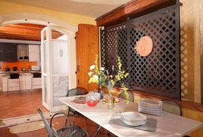 A dining area with a table set for two, a vase with flowers, and a decorative panel with a lion's head. - Borgo del Torchio in Manerba del Garda (Manerba del Garda)