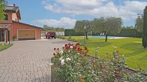 A residential property with a paved driveway, a garage, a swimming pool, and a well-maintained lawn. - Villa Cedro - Gardagate (Verona)