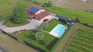 A house with a swimming pool, solar panels, and a red vehicle parked in the driveway. - Villa Cedro - Gardagate (Verona)
