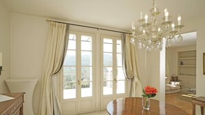 A dining area with a wooden table, a vase with flowers, and a chandelier. - Villa San Carlo - Gardagate (Roe Volciano)