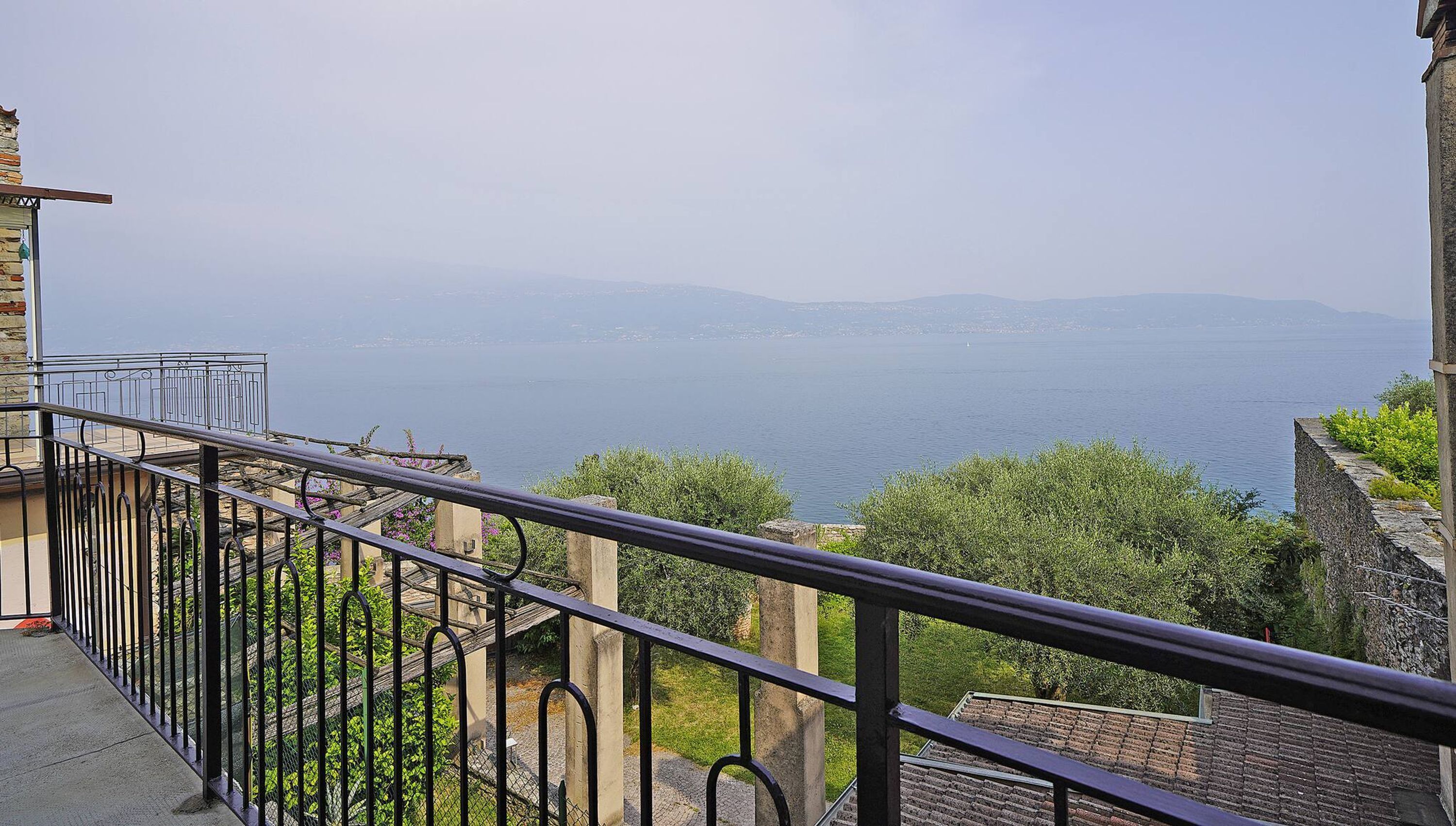 A balcony with a metal railing overlooking a body of water and distant mountains.