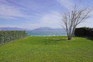 Zona verde con vista al mar y montañas al fondo.