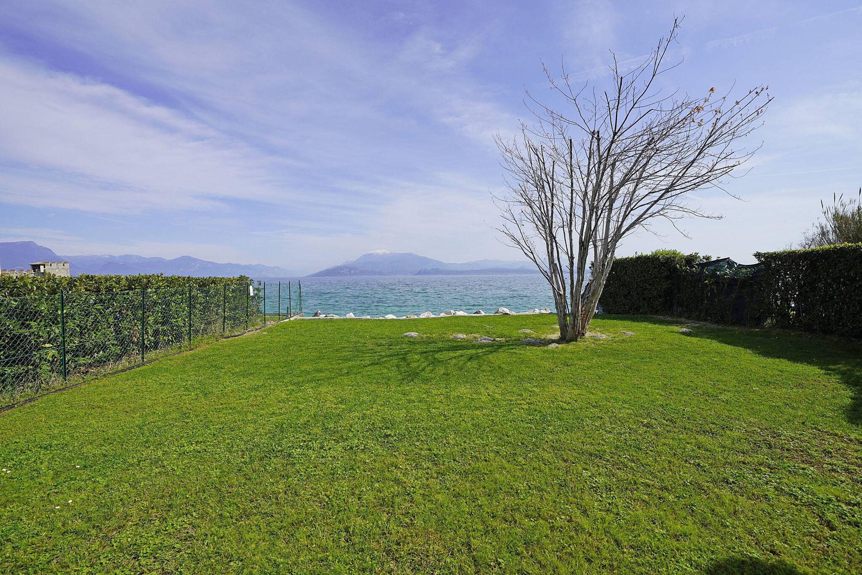Un prato verdeggiante con vista sul mare e sulle montagne.