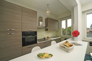 Een moderne keuken met houten kastjes, een inbouwoven, een roestvrijstalen afzuigkap en een wit aanrecht.