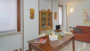 A dining area with a wooden table, chairs, a cabinet with glass doors, and a sofa. - Casa Annalisa in Sal (Salò)