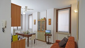 A compact living space with a dining area, a sofa, a television, and a ceiling fan. - Casa Annalisa in Sal (Salò)