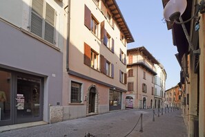 A narrow cobblestone street lined with multi-story buildings, featuring ground-floor shops and upper-floor residential or commercial spaces. - Casa Annalisa in Sal (Salò)