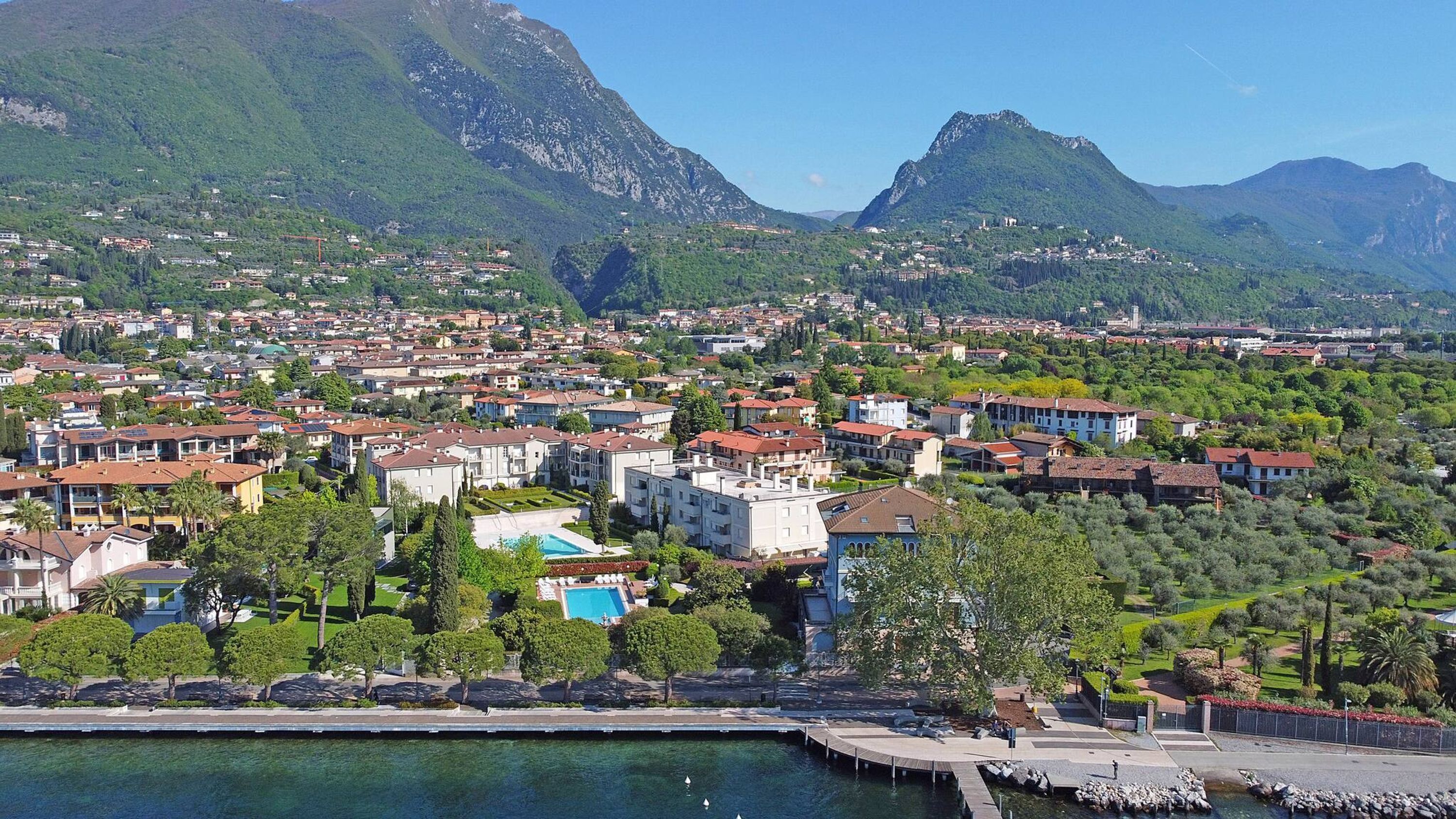 A coastal town with residential buildings, a marina, and mountains in the background.
