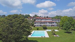 A multi-story hotel with a swimming pool and lush greenery. - Petronella in Soiano (Soiano del Lago)