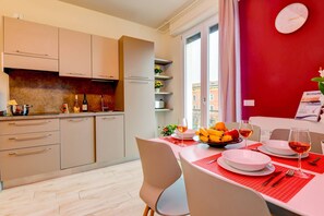 A modern kitchen with beige cabinets, a built-in oven, and a dining area with a red tablecloth. - Casa Vino in Sal With 1 Bedrooms and 1 Bathrooms (Salò)