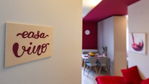 Una stanza con una parete beige e un divano rosso. Sul muro è presente un cartello con la scritta 'easa vivo'.