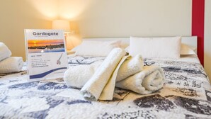 Una camera d'albergo con un letto rifatto, una targa con informazioni dell'hotel e una lampada.