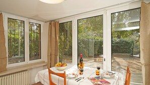 A dining area with a table set for two, a bowl of fruit, a bottle of wine, and a book. - Casa Romantico Eden in Solarolo (Manerba del Garda)