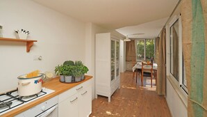 A kitchen with a stove, a pot of spaghetti, and a cabinet. There is a dining area with a table and chairs. - Casa Romantico Eden in Solarolo (Manerba del Garda)