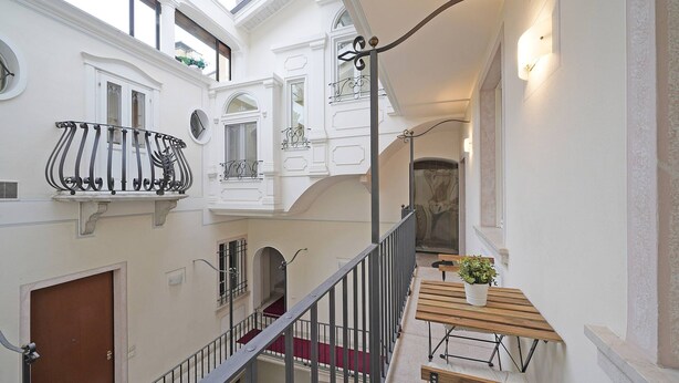 A multi-level interior with a wooden bench and potted plant, white walls, and a staircase. - Downtown Apartment in Sal (Salò)