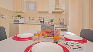 Une cuisine moderne avec des meubles en bois, un four à micro-ondes et un coin repas agrémenté d’assiettes, de couverts et d’un plateau de fruits.