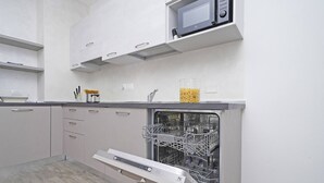 Cocina moderna con armarios blancos, microondas integrado y lavavajillas con escurreplatos.