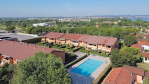 A residential building with a swimming pool, surrounded by greenery and a distant view of a town. - Casa Rudi in Sirmione (Sirmione)