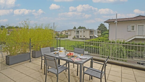 Ein Balkon mit Esstisch und Stühlen, der auf einen Wohnbereich mit Häusern und Grünflächen blickt.