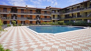 Ein mehrstöckiges Gebäude mit Balkonen, einem Schwimmbecken und einer gefliesten Terrasse.