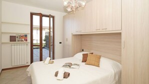 Ein Schlafzimmer mit Bett, einer Chandelieber, einer Heizung und einer Tür, die auf einen Balkon führt.