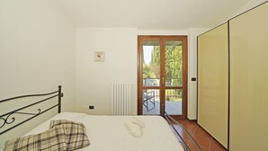 Un dormitorio con cama, radiador, ventana y puerta que da a un espacio exterior.