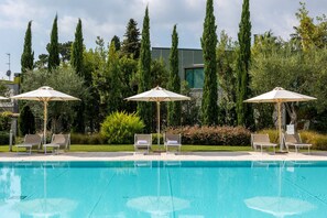 A swimming pool with lounge chairs and umbrellas, surrounded by tall trees and greenery. - Fasanella 50 in Toscolano-maderno (Toscolano Maderno)