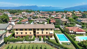 A residential area with a large building featuring a swimming pool and a well-maintained garden. - Susie s Place in Sirmione (Sirmione)