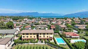 A residential area with a large house featuring a swimming pool, surrounded by smaller houses and lush greenery. - Susie s Place in Sirmione (Sirmione)