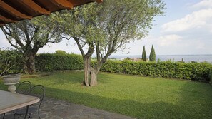 Un patio con mesa y sillas, césped y vista al mar.