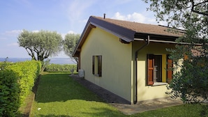 Ein eingeschossiges Haus mit geneigtem Dach, einer kleinen Veranda und Blick aufs Meer.
