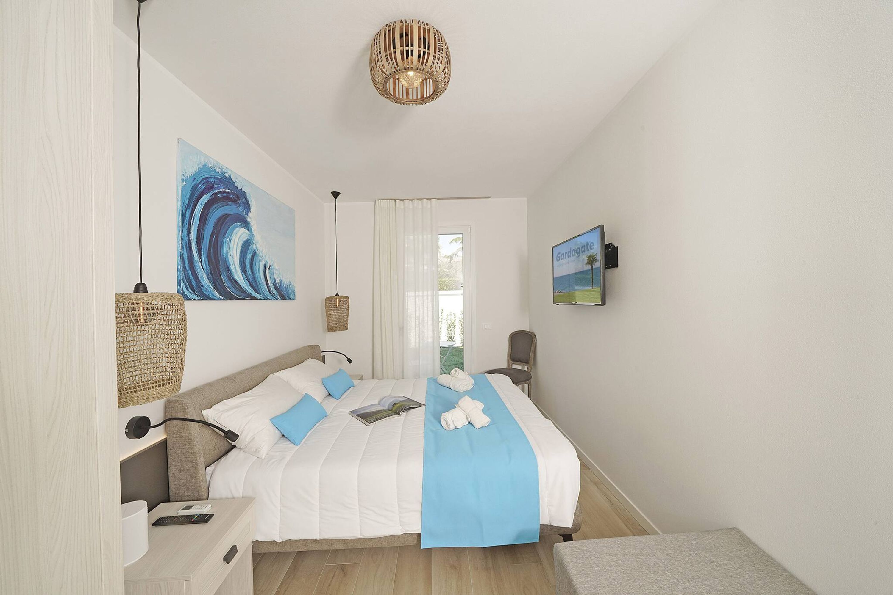 A modern bedroom with a bed, a bedside table, a lamp, and a painting on the wall.