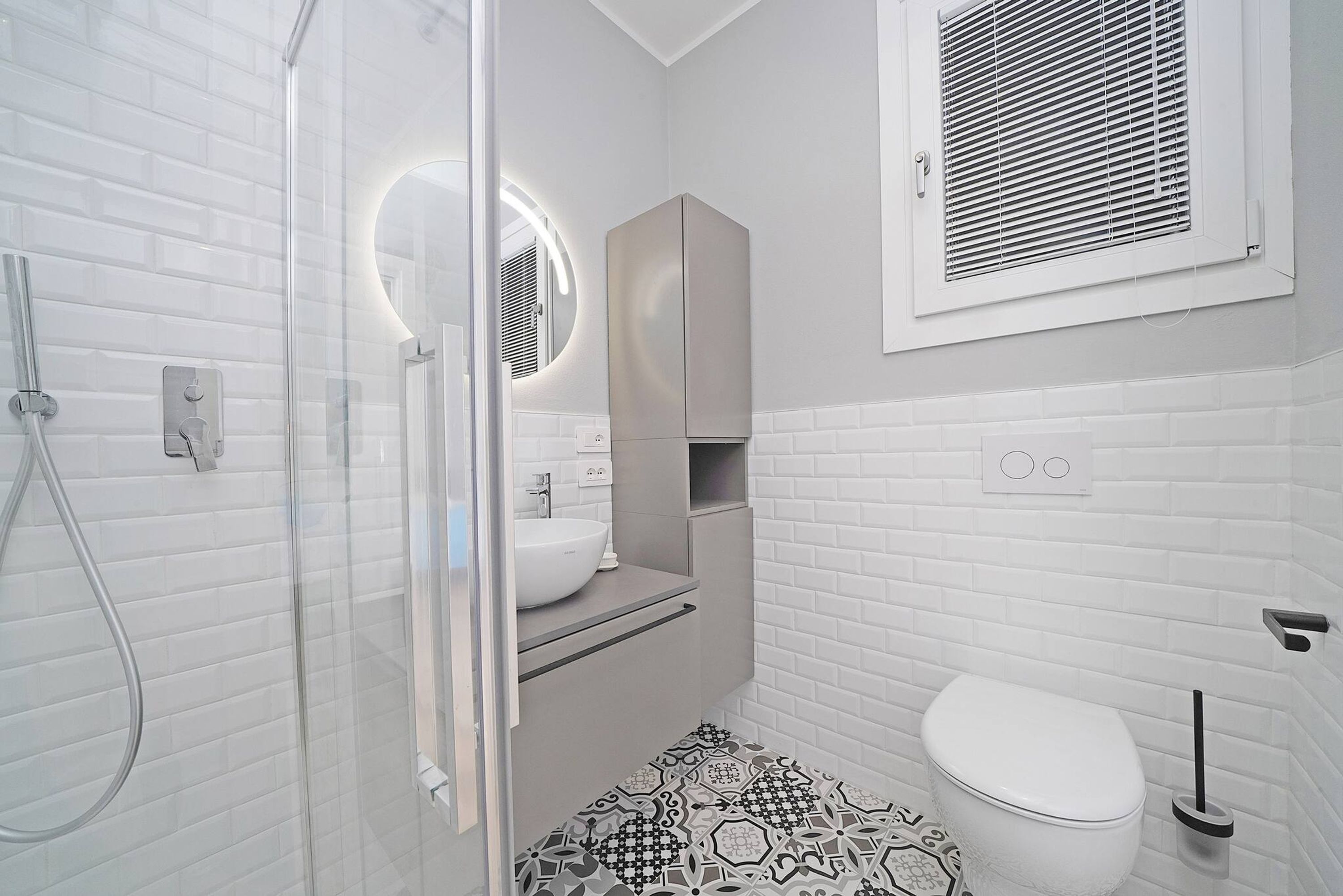 Un bagno moderno con cabina doccia in vetro, un water bianco e un mobile lavabo con specchio.