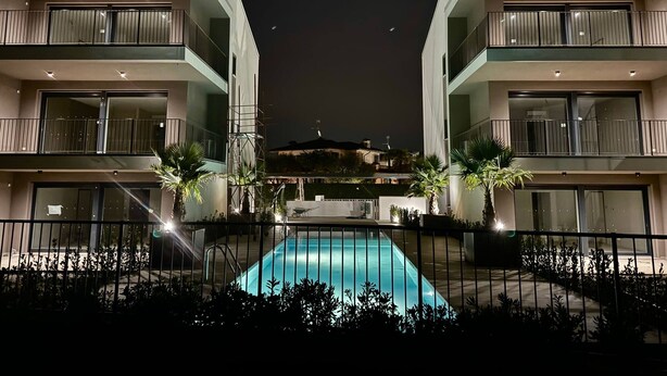 Un edificio moderno con piscina, balcones y vista de la ciudad de noche.