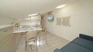Ein kleines Zimmer mit Küchenzeile, Essbereich und Sitzecke.