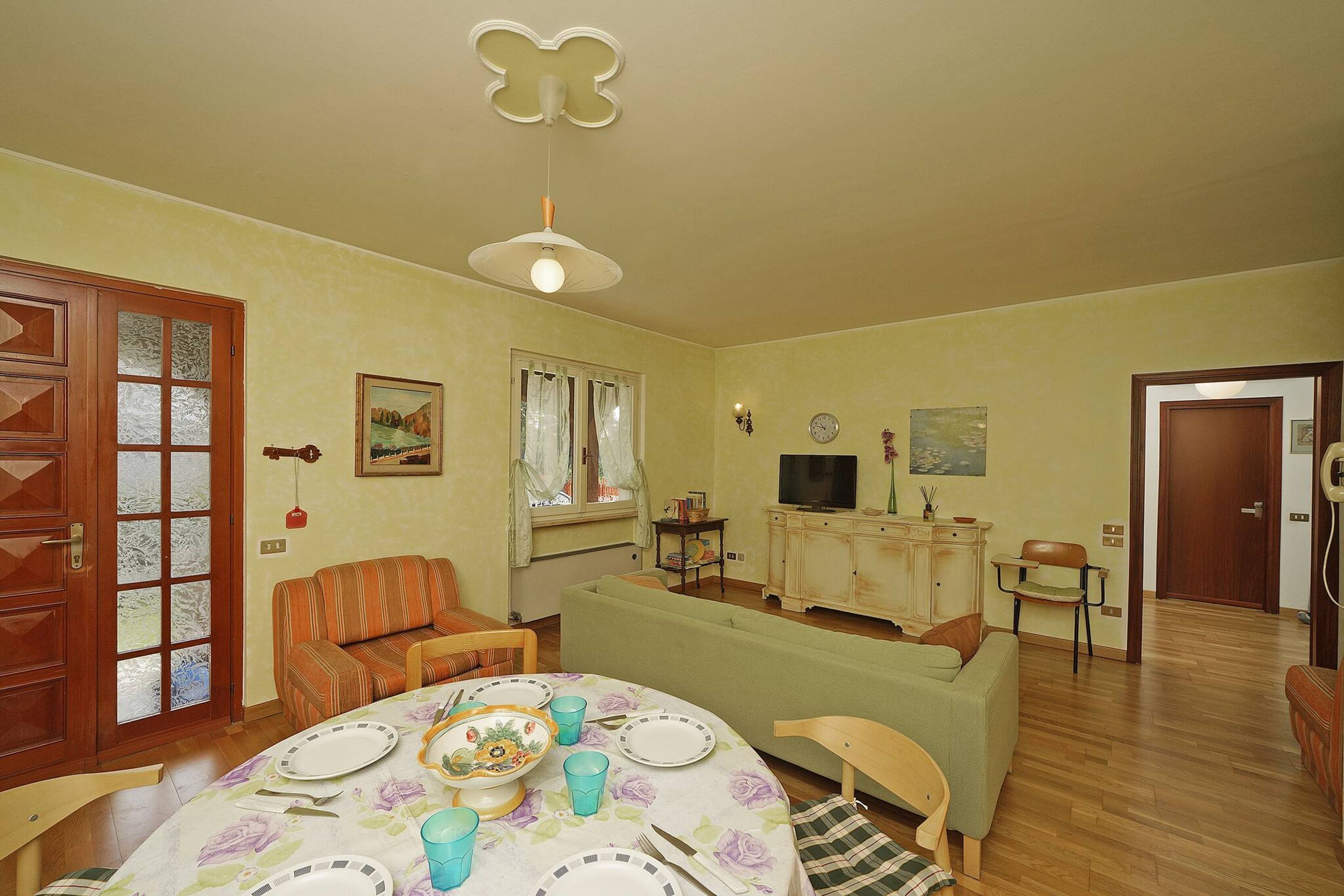 A dining area with a table set for four, a sofa, and a television in the background.