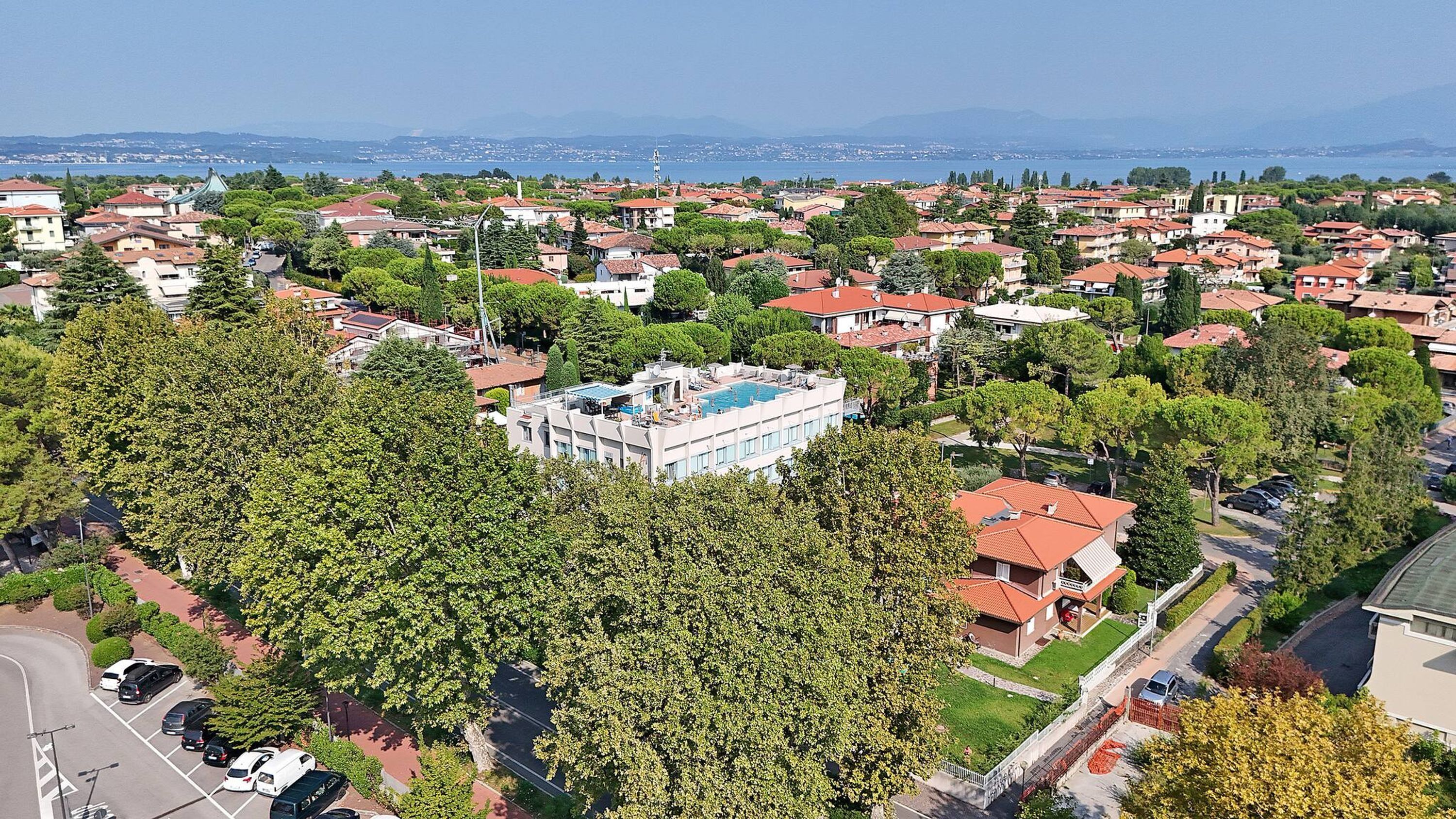 An aerial view of a residential area with houses, a swimming pool, and a large building with a flat roof.