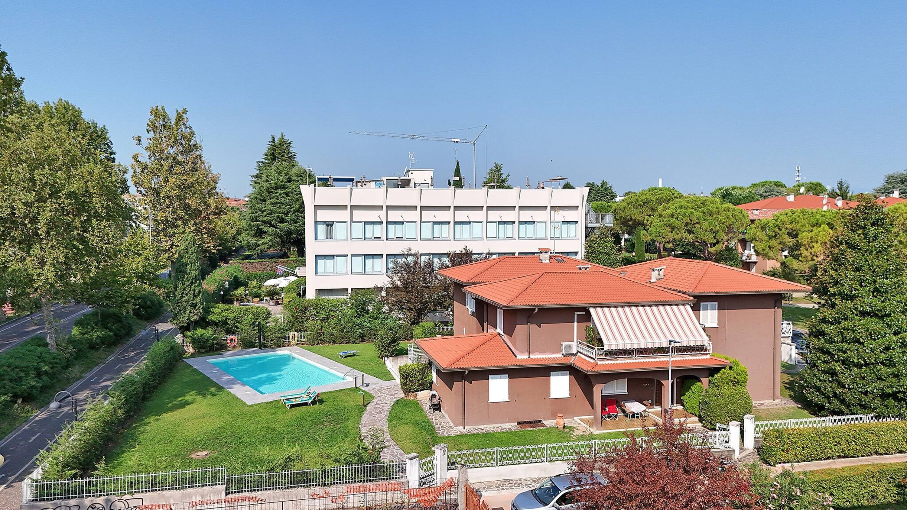 A residential area with a swimming pool, a large building with multiple windows, and a smaller house with a red roof.
