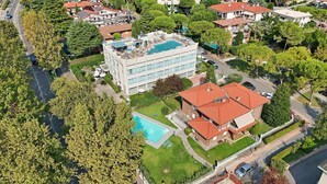 Ein Luftbild eines Wohngebiets mit einem großen Gebäude, das einen Dachpool und ein kleineres, angrenzendes Gebäude mit rotem Dach zeigt.