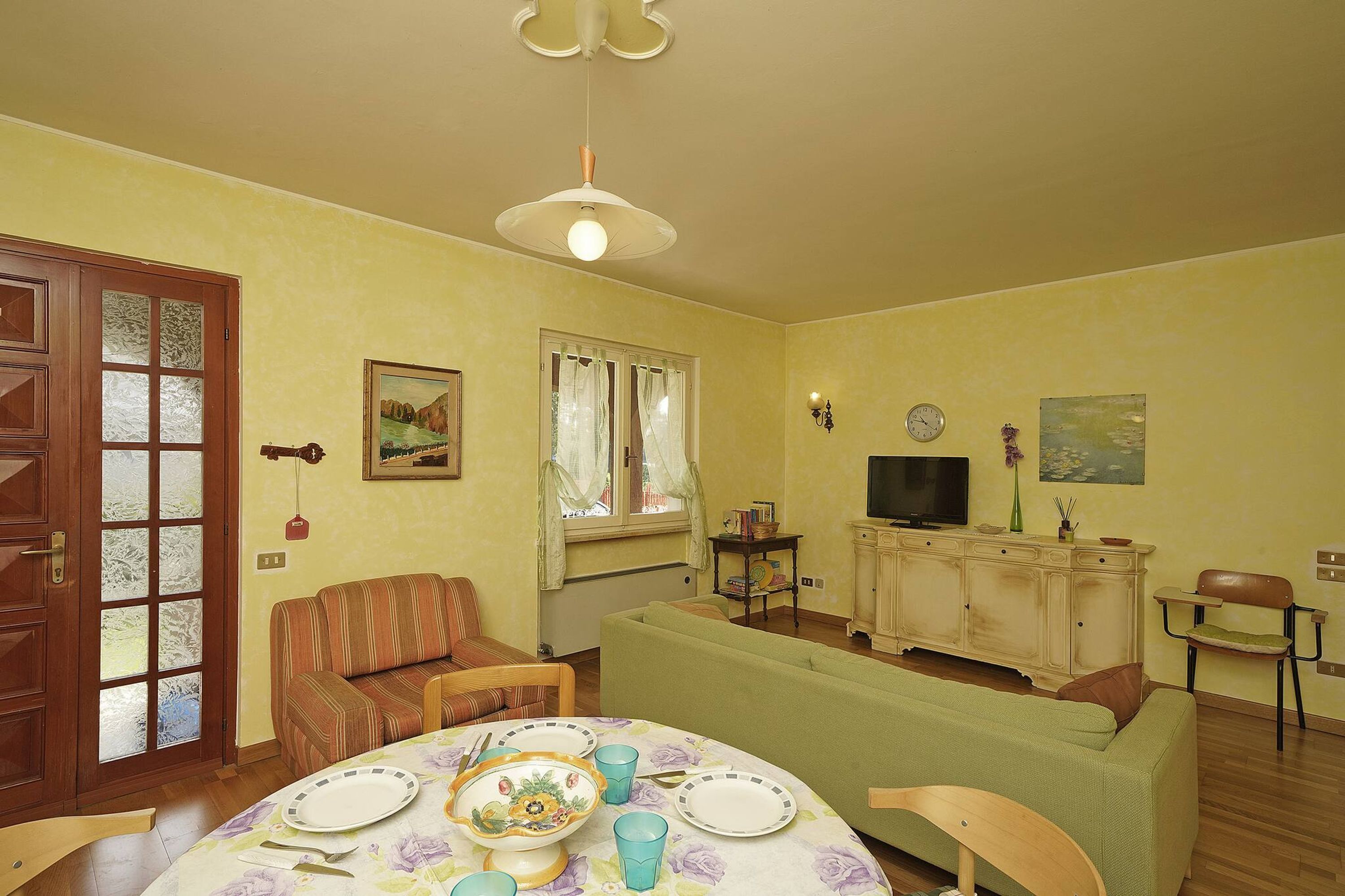 En stue med spisebord, sofa, fjernsyn og skab.