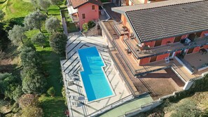 An aerial view of a hotel with a rooftop swimming pool, a garden, and a red building with balconies. - Albatros B8 in Toscolano-maderno (Toscolano Maderno)