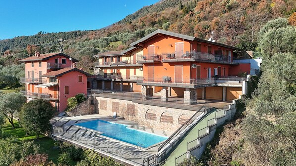 A multi-story building with a swimming pool, balconies, and a hillside backdrop. - Albatros B8 in Toscolano-maderno (Toscolano Maderno)
