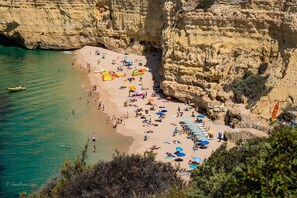 A beach with people, umbrellas, and a boat.