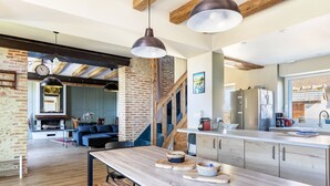 A modern kitchen with a large island, wooden beams, and pendant lighting. - Charming Cottage with Spa for 8–10 Guests, Near Loire Castles (Esvres)