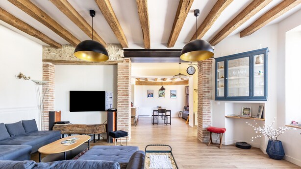 A living room with a sofa, coffee table, TV, and a brick wall. - Charming Cottage with Spa for 8–10 Guests, Near Loire Castles (Esvres)