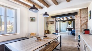 A spacious kitchen with a long wooden table, hanging pendant lights, and exposed brick walls. - Charming Cottage with Spa for 8–10 Guests, Near Loire Castles (Esvres)